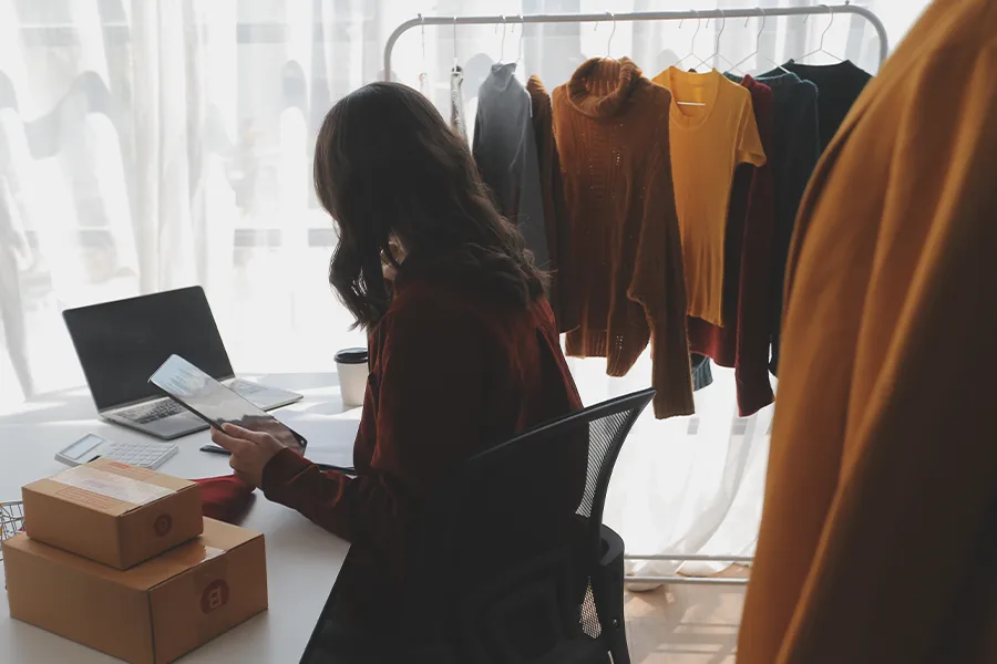 Woman on computer with clothes on rails